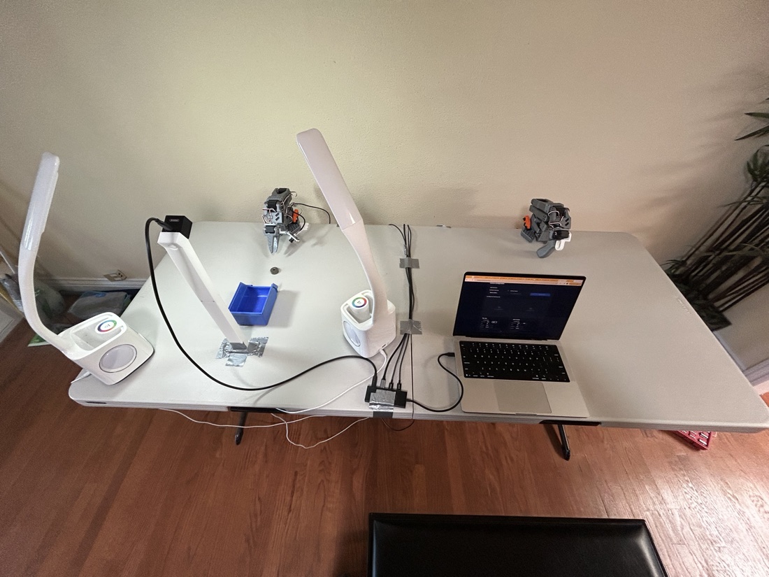 Current setup: two arms on printed mounts, ring lights, an overhead camera, and a parts bin